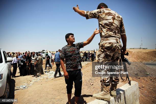 An Iraqi man argues with a Kurdish soldier as Iraqis who have fled recent fighting in the cities of Mosul and Tal Afar try to enter a temporary...