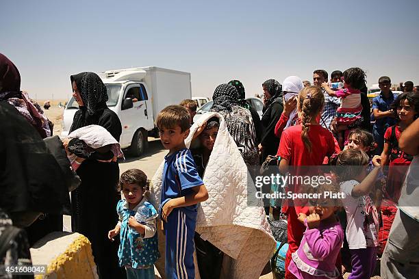 Iraqis who have fled recent fighting in the cities of Mosul and Tal Afar try to enter a temporary displacement camp but are blocked by Kurdish...