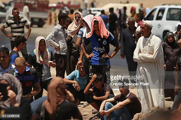 Iraqis who have fled recent fighting in the cities of Mosul and Tal Afar try to enter a temporary displacement camp but are blocked by Kurdish...