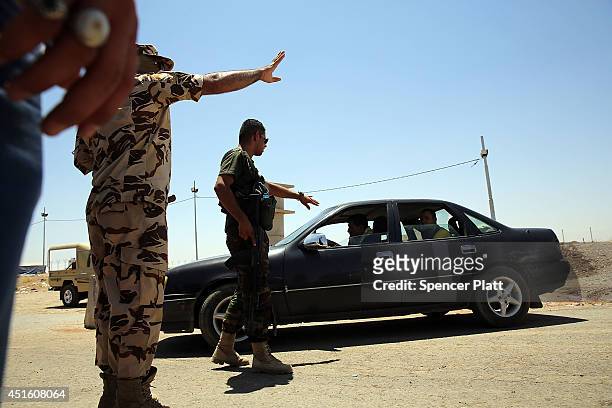 Kurdish soldier turn back cars at a check-point as thousands of Iraqis who have fled recent fighting in the cities of Mosul and Tal Afar try to enter...
