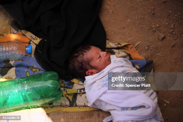 Kazem, a 13 day old girl who is sick, takes shelter under a sheet with her family as thousands of Iraqis who have fled recent fighting in the cities...