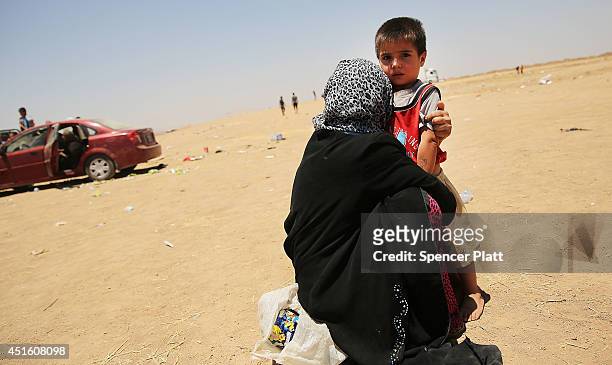 An Iraqi child and his mother wait near a camp entrance as thousands of Iraqis who have fled recent fighting in the cities of Mosul and Tal Afar try...