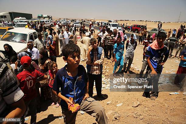 Iraqis who have fled recent fighting in the cities of Mosul and Tal Afar try to enter a temporary displacement camp but are blocked by Kurdish...