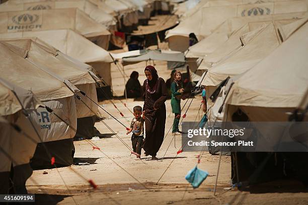 Iraqis who have fled recent fighting walk in a temporary displacement camp on July 2, 2014 in Khazair, Iraq. The displacement camp Khazair is now...