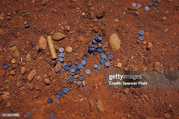 Water bottle caps are viewed on the ground outside of the processing center at a temporary displacement camp on July 2, 2014 in Khazair, Iraq. The...