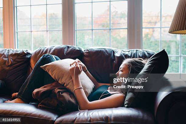 teenage girl listening to music - lying on back girl on the sofa imagens e fotografias de stock