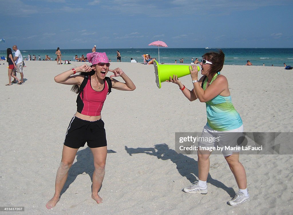 Two young women screaming and laughing on beach