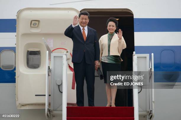 China's President Xi Jinping and his wife Peng Liyuan wave as they disembark from their aircraft upon arrival at Seoul Air Base on July 3, 2014....