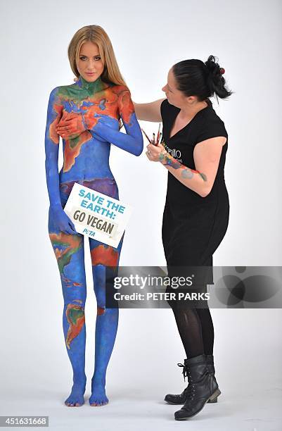 Model Renee Somerfield poses after having her body painted by Jade Little as the earth with a sign reading "Save the Earth, Go Vegan" for a new...