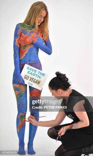 Model Renee Somerfield has her body painted by Jade Little as the earth with a sign reading "Save the Earth, Go Vegan" for a new advertisement by...