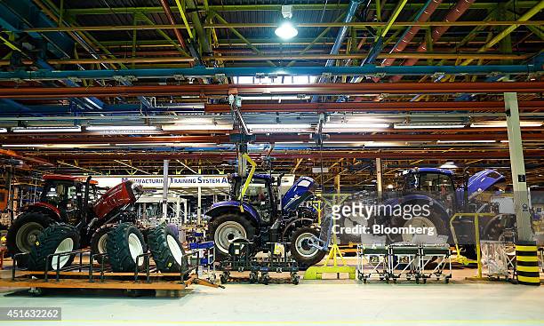 Case IH tractor, left, and New Holland tractors travel along the production line at CNH Industrial NV's assembly plant in Basildon, U.K., on...