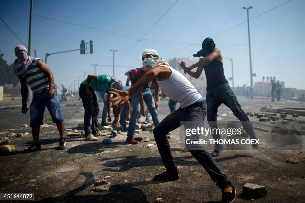 Masked Palestinian protesters throw stones towards Israeli police during clashes in the Shuafat neighborhood in Israeli-annexed Arab East Jerusalem,...