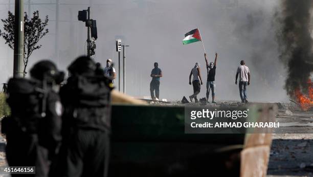 Masked Palestinian protesters throw stones towards Israeli police during clashes in the Shuafat neighborhood in Israeli-annexed Arab East Jerusalem,...