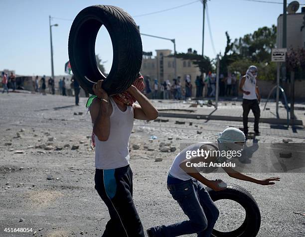 Palestinian youths roll tires towards Israeli security forces during the clashes over the abduction and killing of a Palestinian teen by suspected...