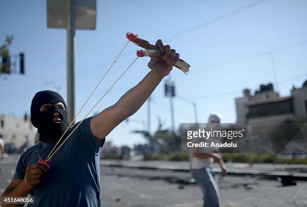 Palestinian man uses slingshot tu hurl stones at Israeli security forces during the clashes over the abduction and killing of a Palestinian teen by...