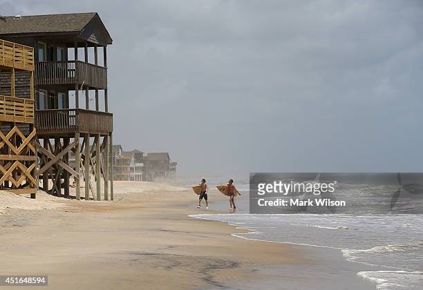 Surfers David Grimes and William Troy walk down the beach while mandatory evacuation orders are in effect for Hatteras Island, July 3, 2014 in...