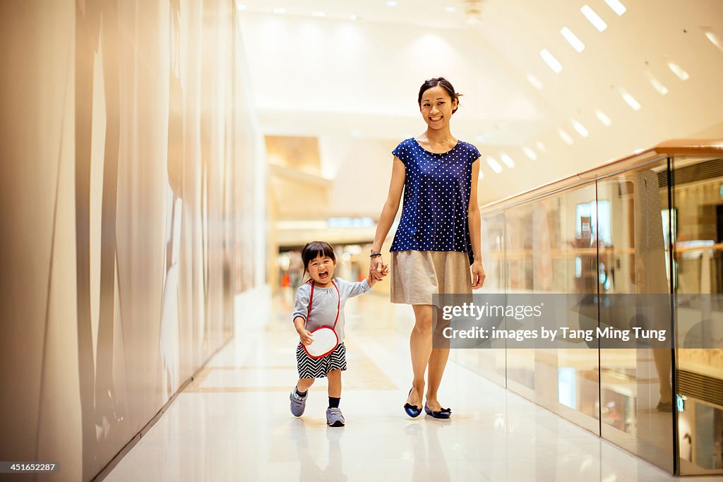 Mom and toddler girl walking in shopping mall