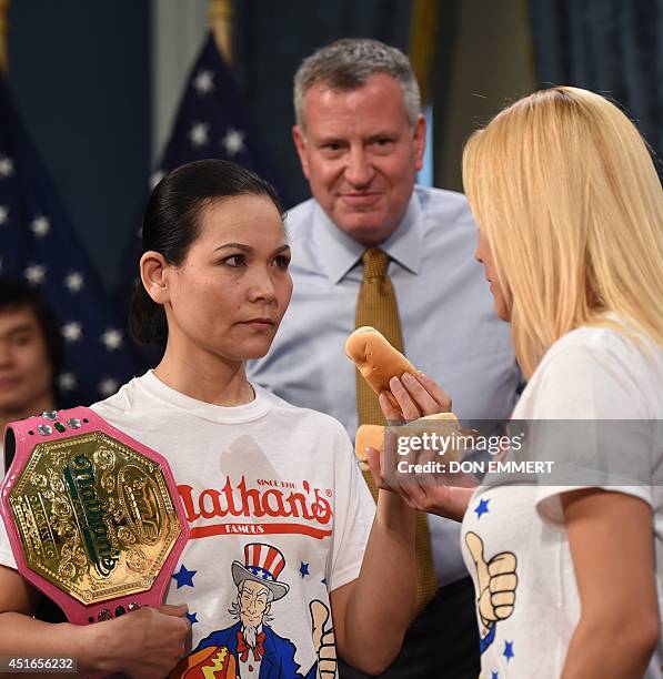 New York City Mayor Bill de Blasio watches as 2013 Nathan's Famous hot dog-eating women's champion Sonya "The Black Widow" Thomas and challenger Miki...