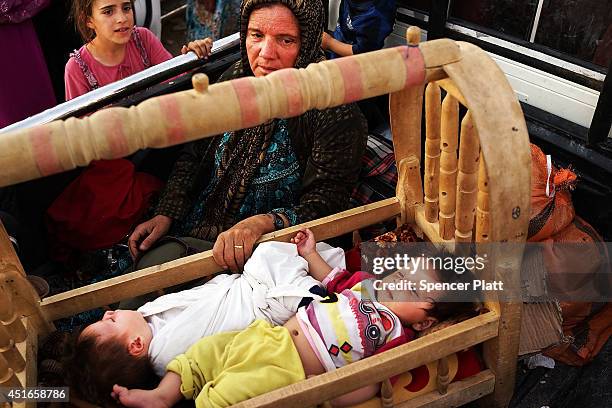 An Iraqi mother who fled recent fighting in the city of Tal Afar rocks her twin children in the back of a pick-up truck as they try to enter a...
