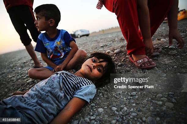 Iraqi children who fled recent fighting near the city of Mosul prepare to sleep on the ground with their family as they try to enter a temporary...