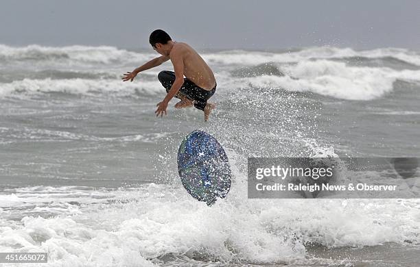 Michael Rhue from Newport, N.C., gets air as he rides his skim board in the rough waves generated by the arrival of Hurricane Arthur in Atlantic...