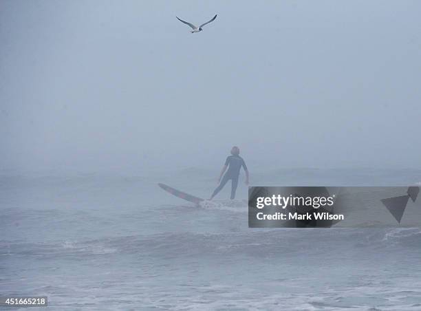 Man surfs in the fog as strong winds and heavy surf from Hurricane Arthur begin to roll in, July 3, 2014 in Nags Head, North Carolina. Hurricane...