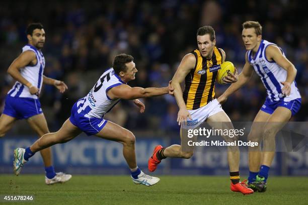 Matt Suckling of the Hawks runs with the ball away from Sam Mitchell of the Hawks during the round 16 AFL match between North Melbourne Kangaroos and...