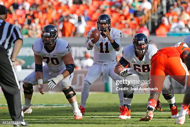 Greyson Lambert takes the snap from Luke Bowanko of the Virginia Cavaliers during fourth quarter action against the Miami Hurricanes on November 23,...