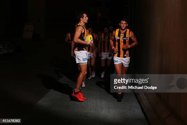Luke Hodge of the Hawks and Angus Litherland lead the team out at half time during the round 16 AFL match between North Melbourne Kangaroos and the...