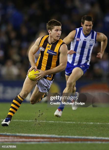Ben Ross of the Hawks runs with the ball away from Sam Gibson of the Kangaroos during the round 16 AFL match between North Melbourne Kangaroos and...