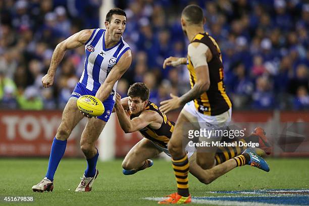 Michael Firrito of the Kangaroos handballs away from Luke Breust of the Hawks during the round 16 AFL match between North Melbourne Kangaroos and the...