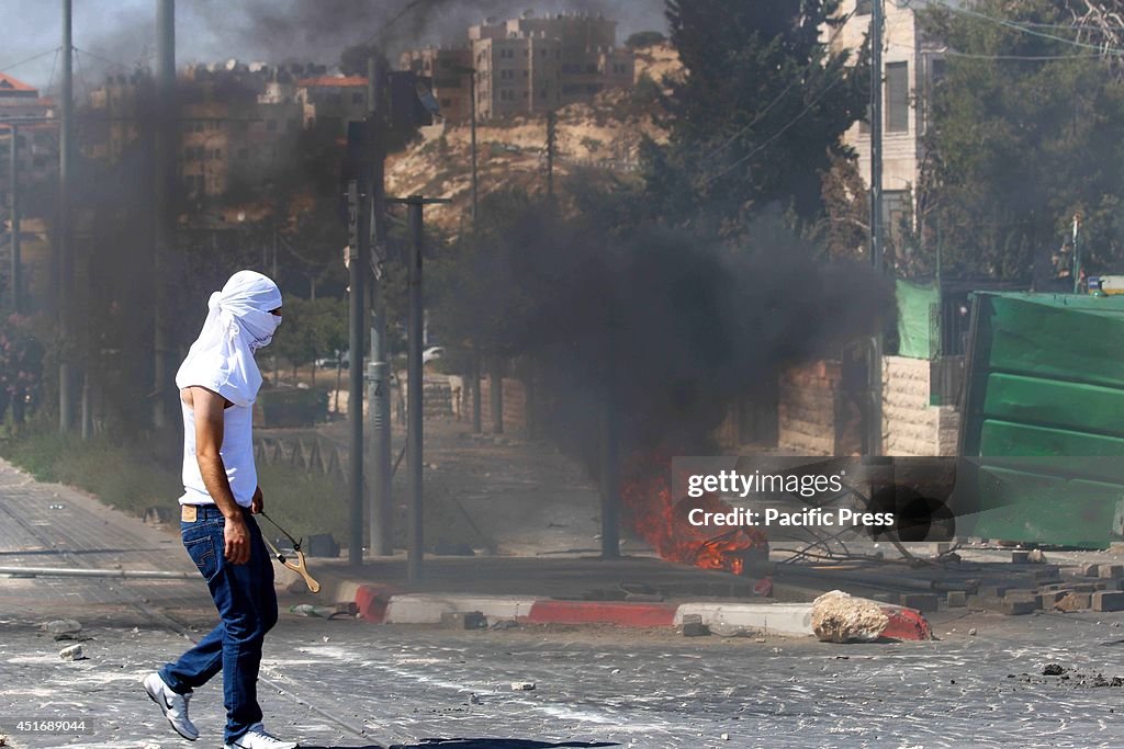 A Palestinian youth holds a hand-made slingshot. Clashes...