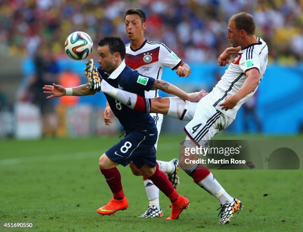 Mathieu Valbuena of France is challenged by Mesut Oezil and Benedikt Hoewedes of Germany during the 2014 FIFA World Cup Brazil Quarter Final match...
