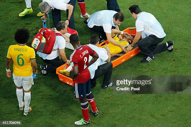 Brazil receives treatment in a stretcher as teammate Marcelo and Cristian Zapata of Colombia look on during the 2014 FIFA World Cup Brazil Quarter...