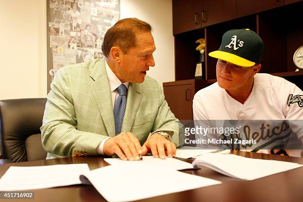 Oakland Athletics first round draft pick Matt Chapman goes over his first MLB contract with agent Scott Boras prior to the game against the Texas...