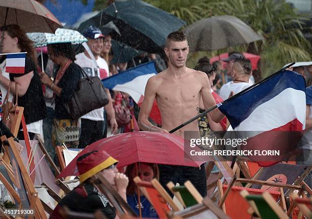 Fans attend under the rain a public viewing ahead of the FIFA World Cup 2014 quarter final match between Germany and France on a giant screen in...