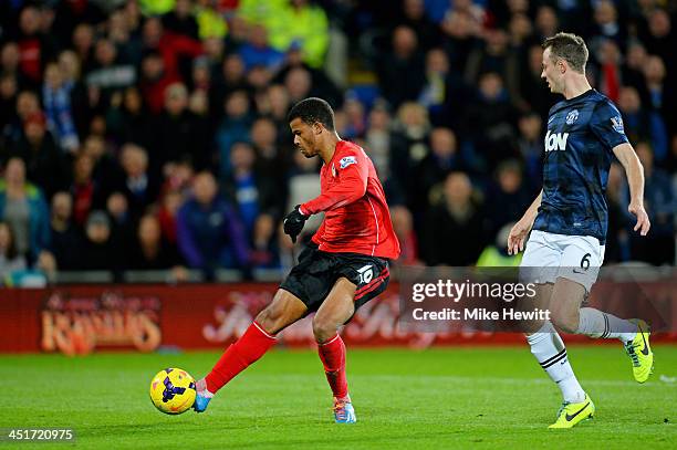 Fraizer Campbell of Cardiff shoots past Jonny Evans of Manchester United to score a goal to level the scores at 1-1 during the Barclays Premier...