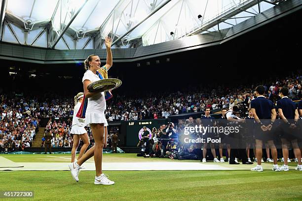 Petra Kvitova of Czech Republic waves to the fans as she walks of court holding the Venus Rosewater Dish trophy after her victory in the Ladies'...