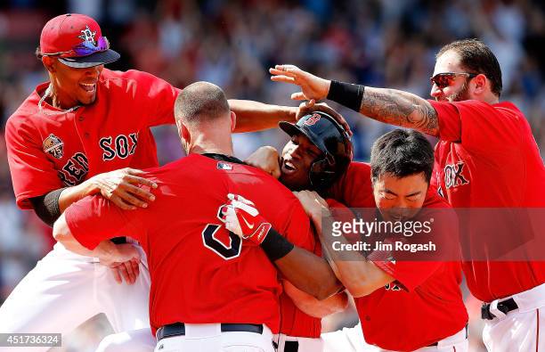 Jonathan Herrera of the Boston Red Sox celebrates with teammates after he singled in the winning run in the ninth inning during the first game of a...