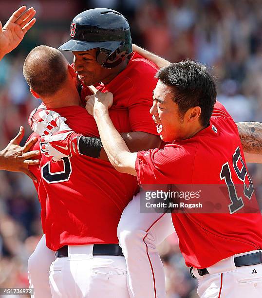 Koji Uehara of the Boston Red Sox jumps on Jonathan Herrera of the Boston Red Sox after he singled in the winning run in the ninth inning during the...
