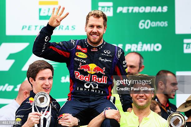 Race winner Sebastian Vettel of Germany and Infiniti Red Bull Racing celebrates on the podium with team mates following the Brazilian Formula One...