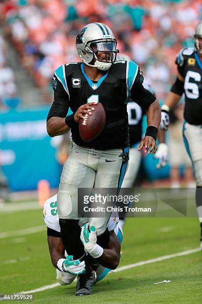 Cam Newton of the Carolina Panthers is tackled by Dion Jordan of the Miami Dolphins at Sun Life Stadium on November 24, 2013 in Miami Gardens,...