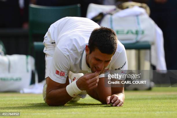 Serbia's Novak Djokovic eats the grass as he celebrates winning his men's singles final match against Switzerland's Roger Federer on day thirteen of...