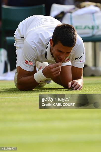 Serbia's Novak Djokovic eats the grass as he celebrates winning his men's singles final match against Switzerland's Roger Federer on day thirteen of...