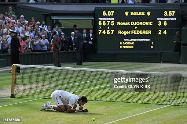 Serbia's Novak Djokovic eats the grass as he celebrates winning his men's singles final match against Switzerland's Roger Federer on day thirteen of...