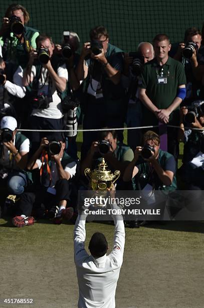 Photographers take pictures of Serbia's Novak Djokovic as he kisses the winner's trophy after beating Switzerland's Roger Federer in the men's...