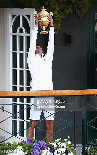 Novak Djokovic of Serbia celebrates with the trophy on the clubhouse balcony after winning the Gentlemen's Singles Final against Roger Federer of...