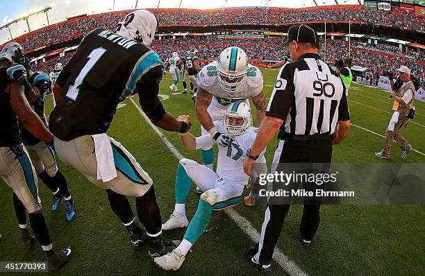 Cam Newton of the Carolina Panthers helps up Ryan Tannehill of the Miami Dolphins during a game at Sun Life Stadium on November 24, 2013 in Miami...