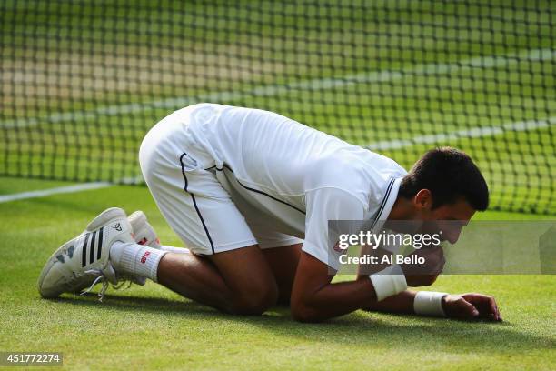 Novak Djokovic of Serbia eats some of the centre court grass as he kneels on the floor as he celebrates winning the Gentlemen's Singles Final match...
