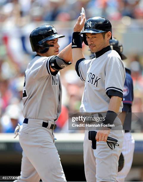 Ichiro Suzuki of the New York Yankees congratulates teammate Jacoby Ellsbury on three-run home run against the Minnesota Twins during the second...